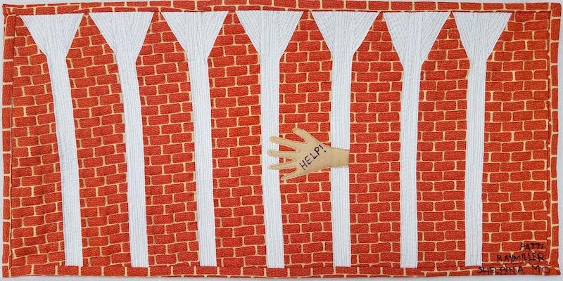 This brick's design is quite literal, using brick motif fabric with a hand reaching through a gap, pleading for help.